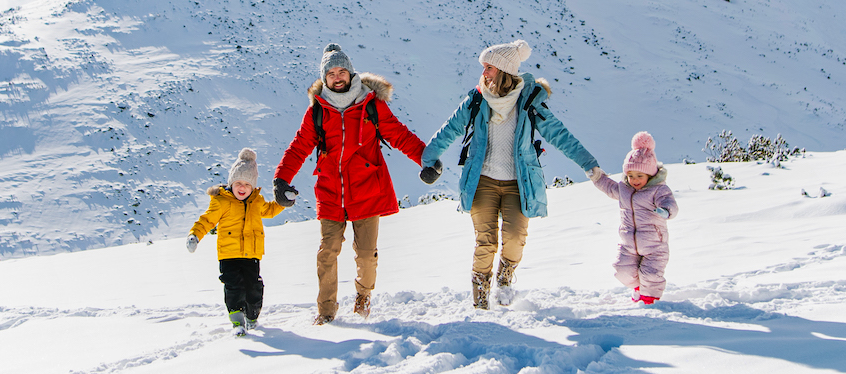 A family enjoying a ski trip at Isola 2000 in the scenic Alpes-Maritimes Provence-Alpes-Côte d’Azur region of France with stunning winter landscapes and a chalet in the background.