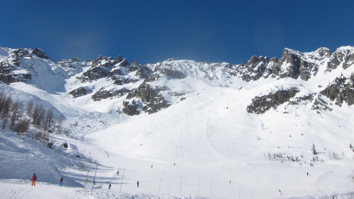 Brévent Flégère in France - a group of people skiing down a snow covered mountain.