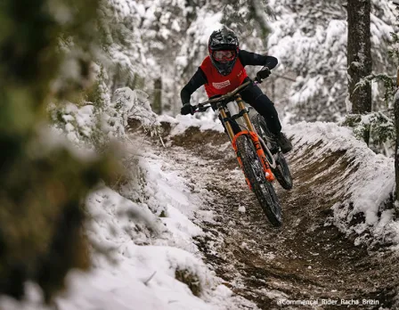 A mountain biker riding on a hill at Pal Arinsal – La Massana in Andorra, with traces of winter sports and a chalet in the distance.