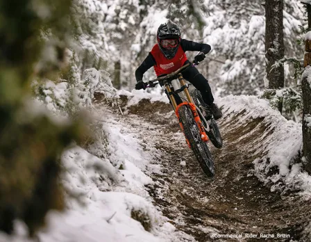 A mountain biker riding on a hill at Pal Arinsal – La Massana in Andorra, with traces of winter sports and a chalet in the distance.
