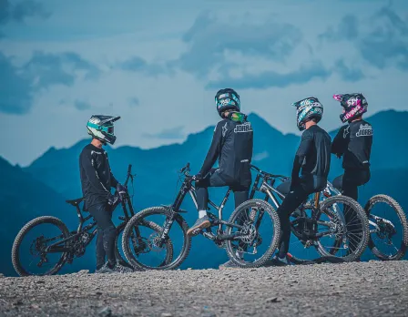A mountain biker riding through Pal Arinsal – La Massana in Andorra with a faint view of a chalet and mountain in the background.