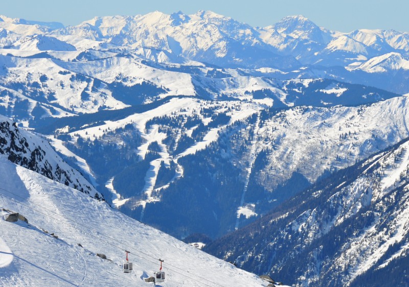 View of a chalet at Les Houches Saint-Gervais ski resort in France. The wintery scene includes skiers and a ski lift on snow-covered slopes.