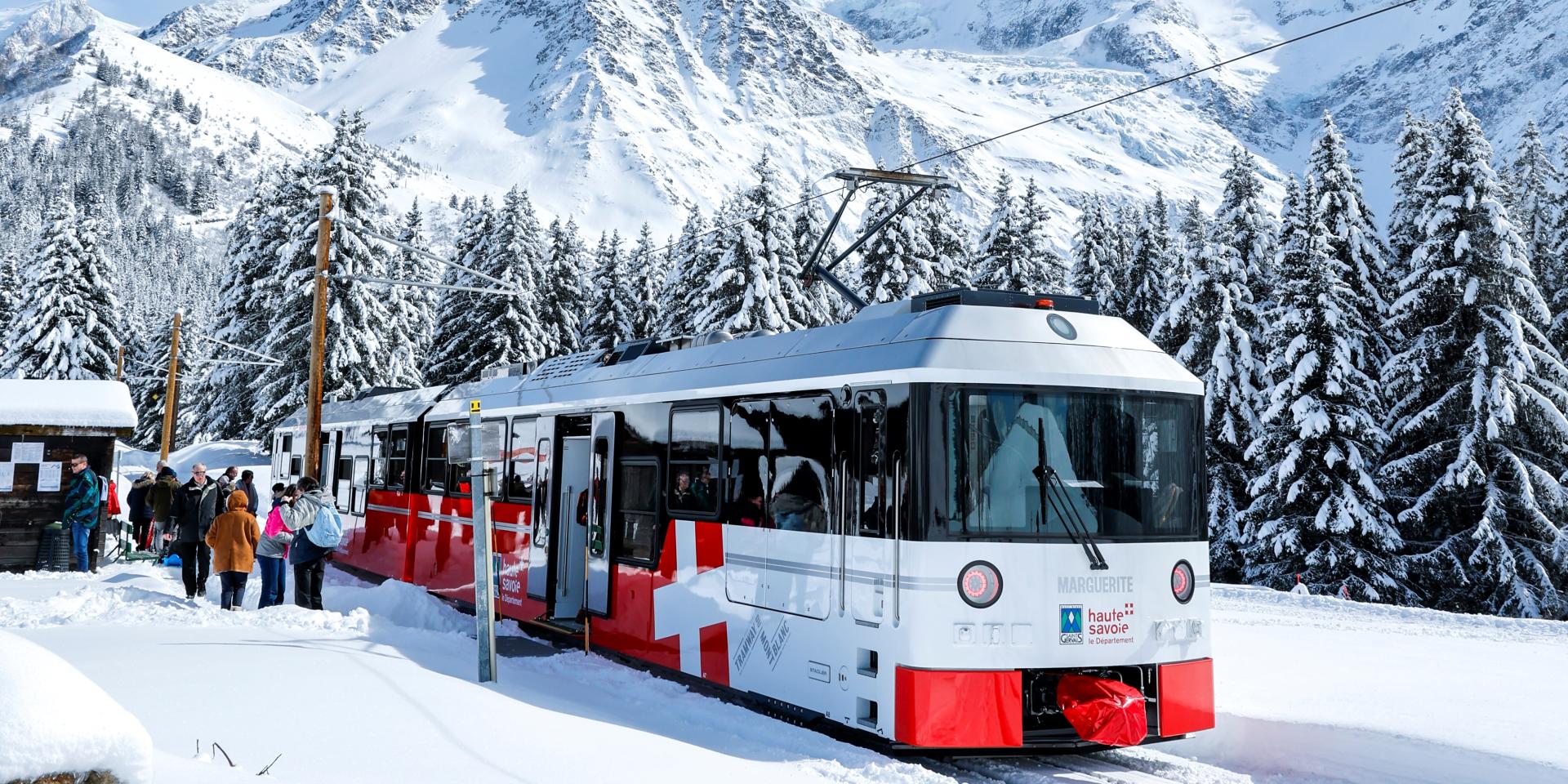 Les Houches Saint-Gervais in France - a red and white train traveling through snow covered mountains.