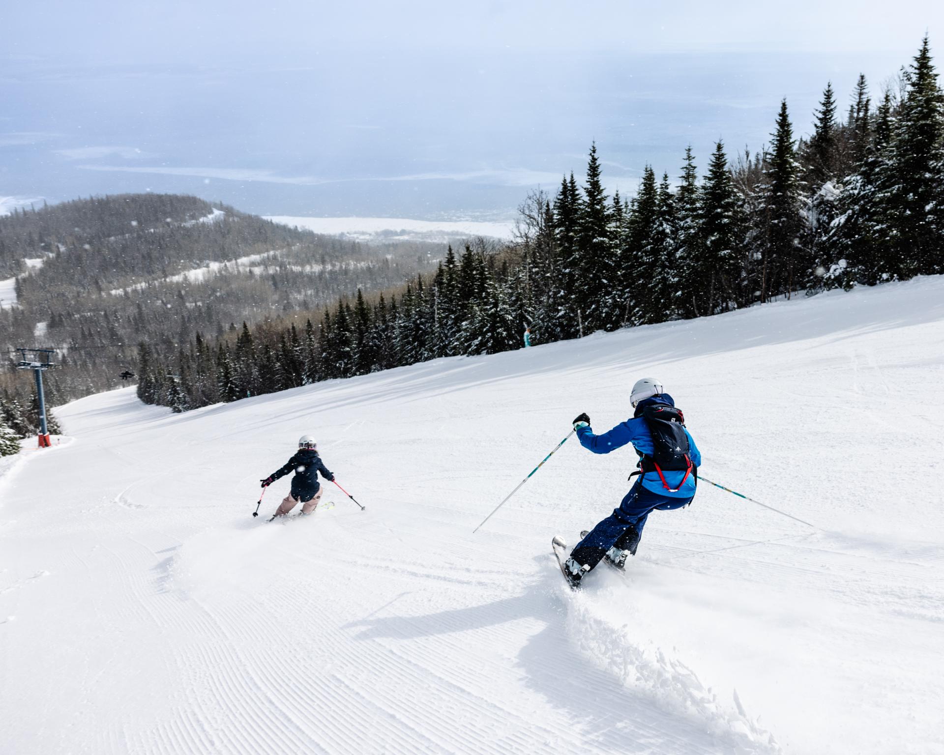 Le Massif de Charlevoix in Canada - a couple of people skiing down a snowy slope.