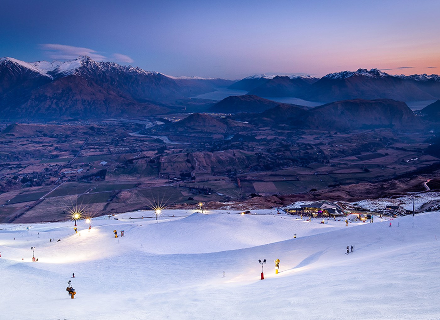 Coronet Peak in New Zealand - a group of people skiing down a snow covered mountain.