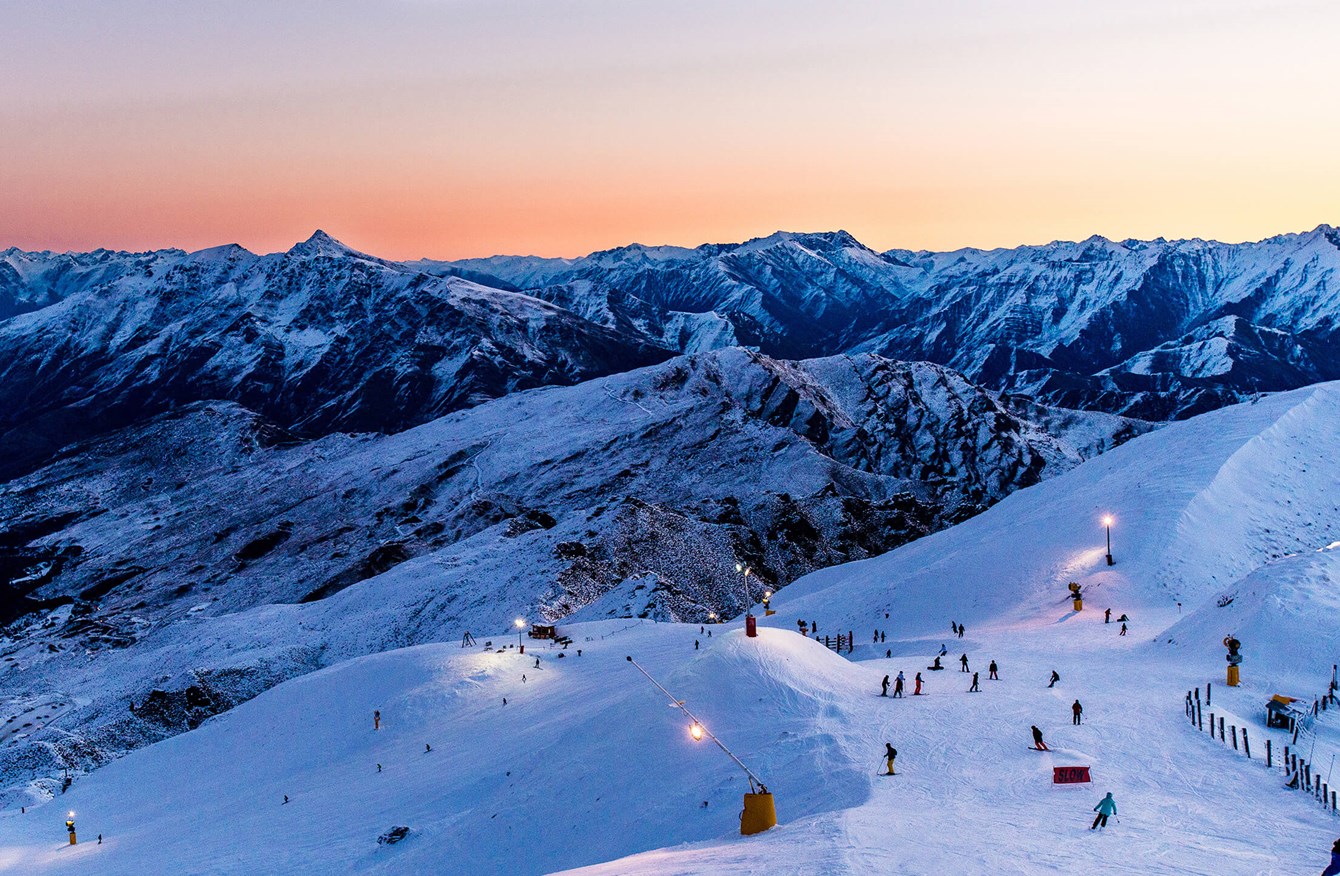 Coronet Peak in New Zealand - a group of people skiing down a snowy mountain.