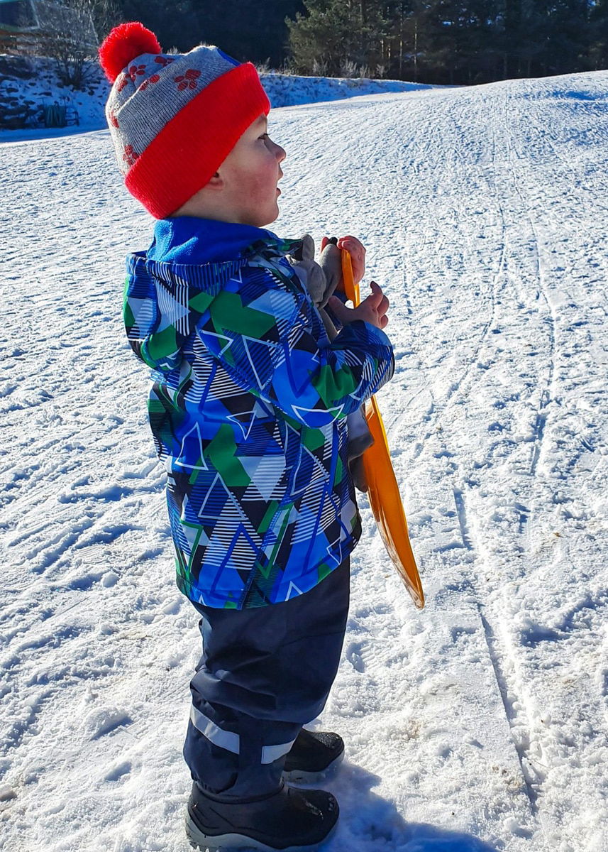 Čelimbaša in Croatia - a little boy standing in the snow holding a carrot.