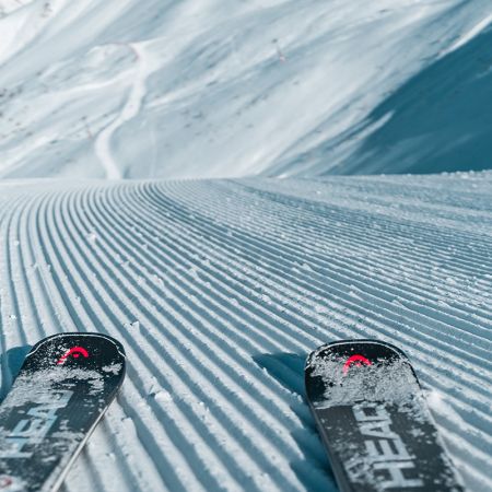 A skier is gracefully gliding down the snowy slopes at Les Orres ski resort in France, surrounded by pristine, snow-covered terrain and charming chalets.