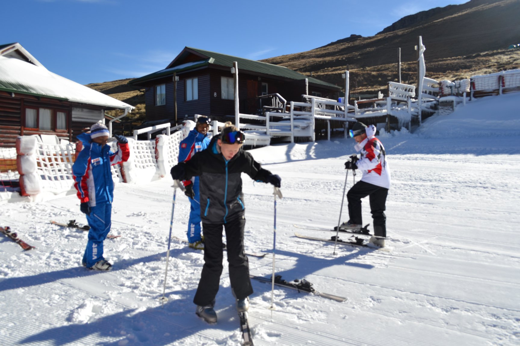 A lively scene at Tiffindell in Barkly East South Africa showcasing a winter sports centre a ski resort with numerous skiers enjoying the snow. A quaint chalet adds a charming element.