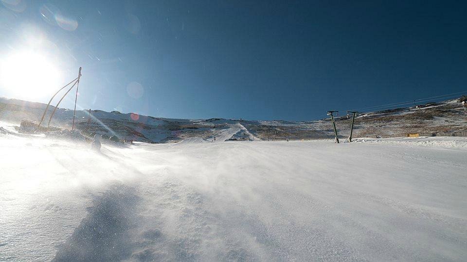 Winter sports scene at Tiffindell, Barkly East, South Africa featuring a ski resort with participants enjoying the slopes, a challet, and surrounding mountain.