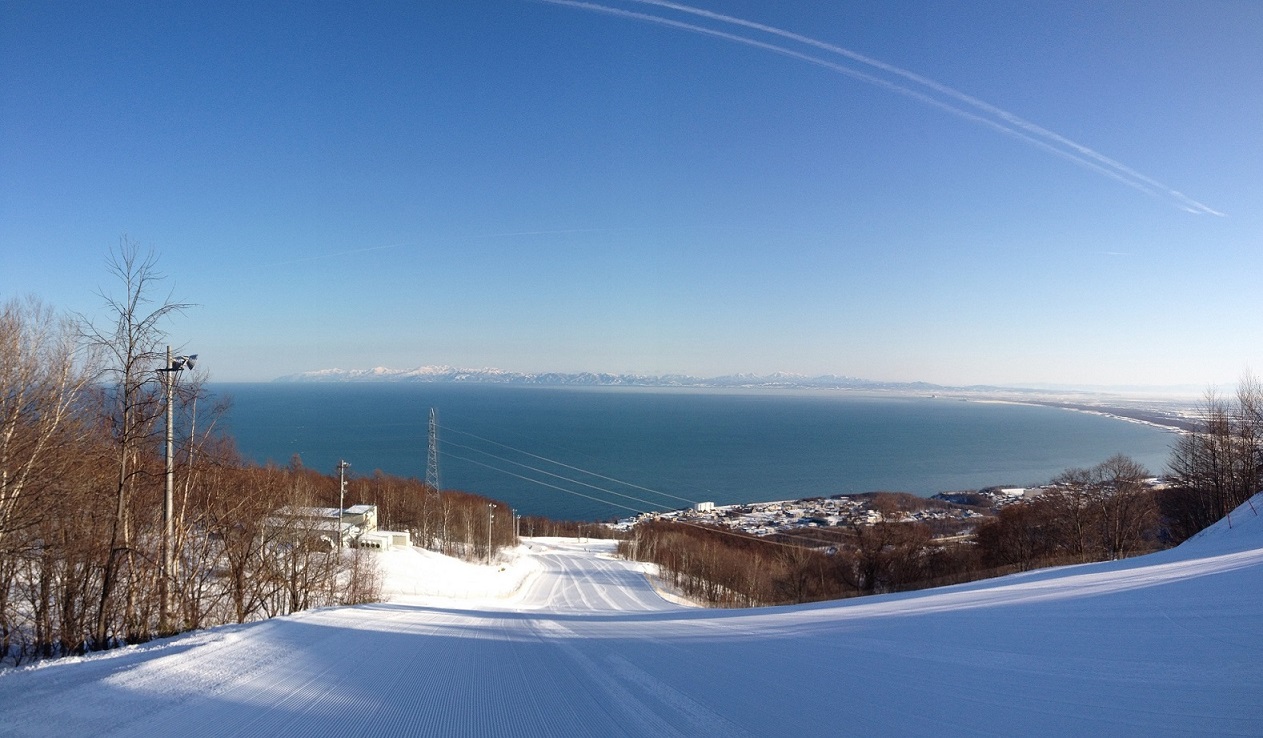 Snow Cruise Onze in Japan - a ski slope with a view of the ocean and mountains.