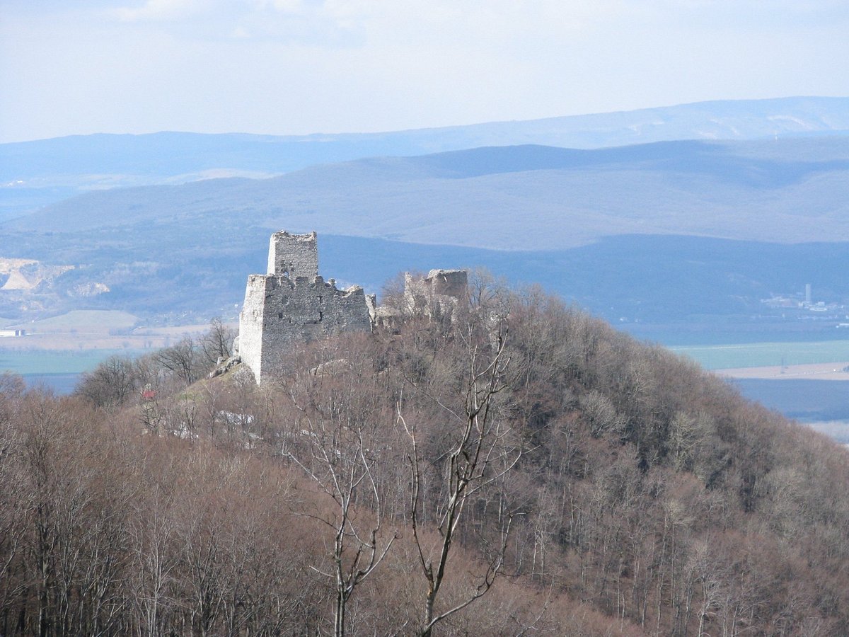 Bezovec in Slovakia - a castle on top of a hill with mountains in the background.
