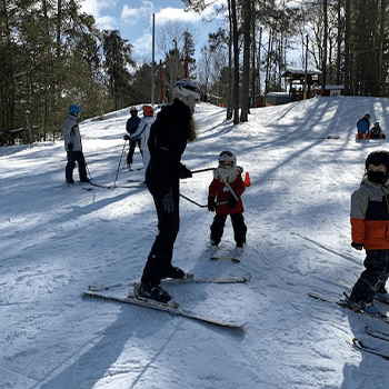 A family enjoys skiing amidst the white expanse of Mount Martin Deep River in Southern Ontario Canada. The picture captures winter sports enthusiasm at a ski resort with a child learning to ski in the scene.