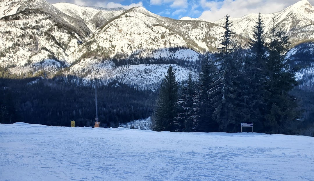 A skier in action at Summit Lake – Nakusp ski resort in the Kootenay Rockies, British Columbia, Canada. The image captures the glistening, snow-covered slopes in a beautiful winter sports scene.