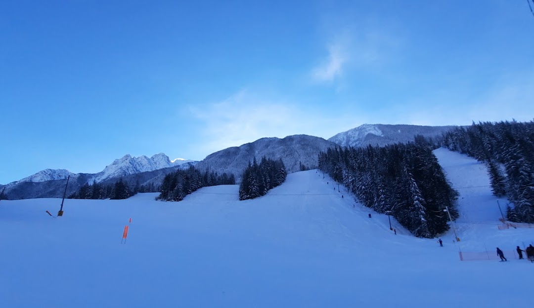 A serene winter sports scene at Summit Lake Nakusp in Kootenay Rockies British Columbia Canada featuring a ski resort with a charming chalet all against the backdrop of a majestic mountain.
