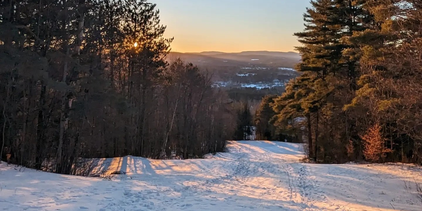 Lyndon Outing Club in USA - the sun is setting on the snow covered trail.