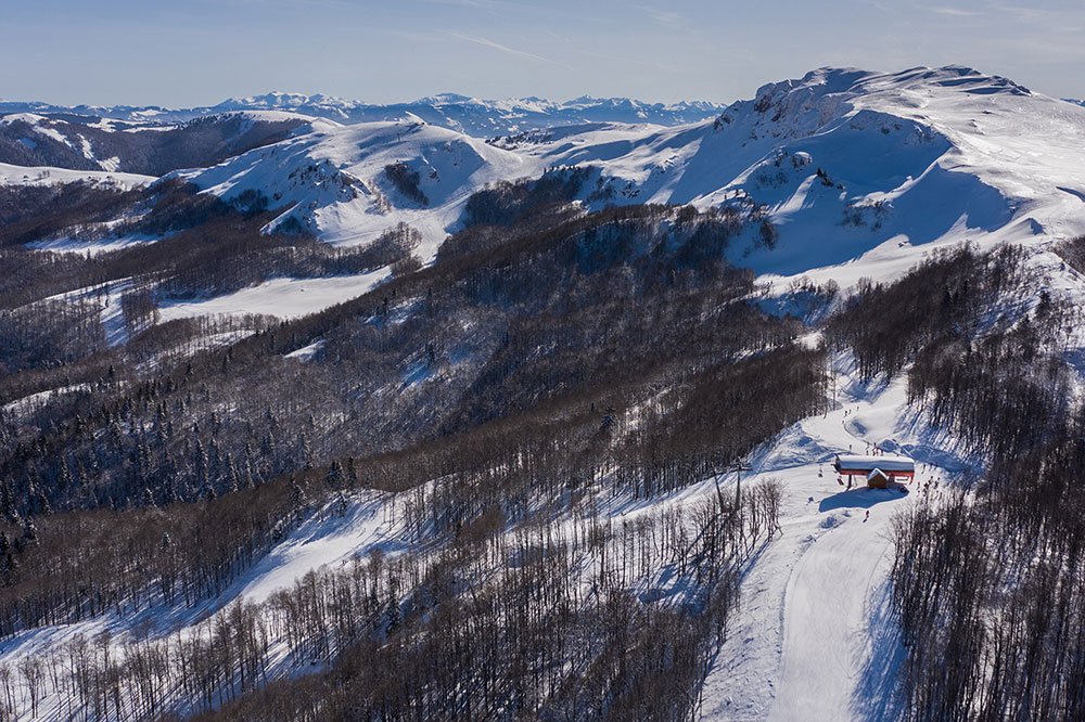 View of Kolašin 1450 | Kolašin 1600 ski resort in Montenegro featuring ski lifts, skiers on the slope, and picturesque winter scenery.