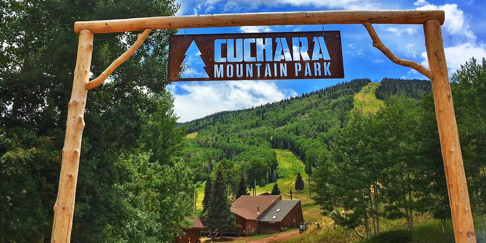 A scenic view of Cuchara Mountain Park in Colorado featuring a ski resort with a chalet nestled at the base of a vibrant mountain under a clear blue sky.