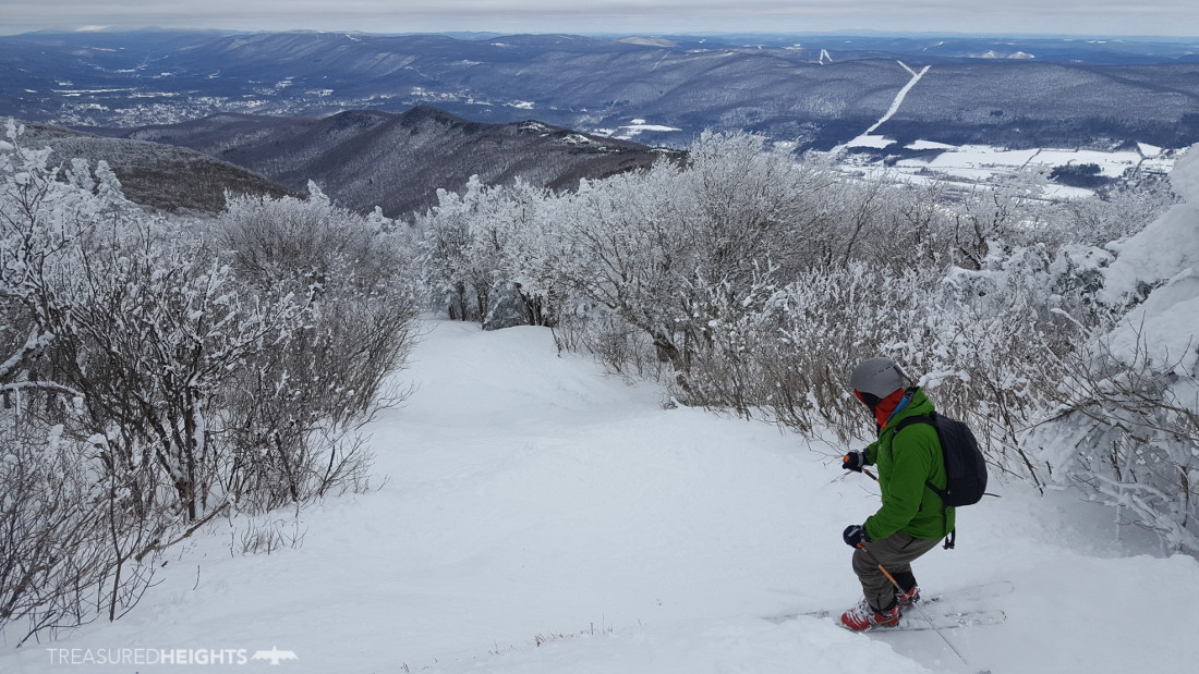 Skier and snowboarder enjoying winter sports at Mount Greylock, South Williamstown, MA, amidst stunning snowy woodland scenery at the ski resort.
