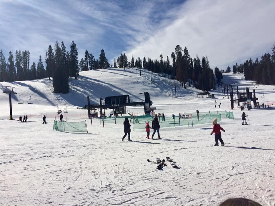 Winter scene at Badger Mountain, Washington State, predominantly showcasing a lively sports scene with skiers enjoying the slopes and a ski resort seated beneath the mountain peaks.