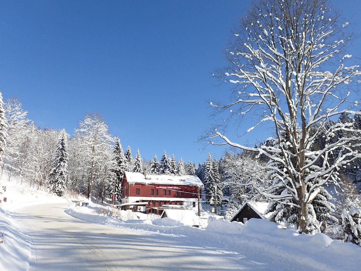 Černá Říčka in Czech Republic - a snowy road with a red house in the background.