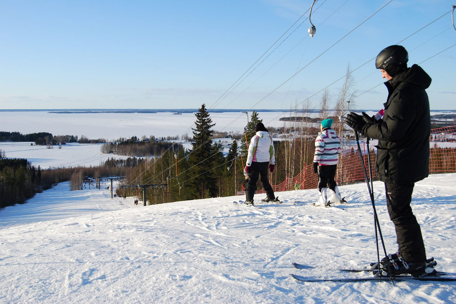 Lakis in Finland - a group of people skiing down a snowy hill.