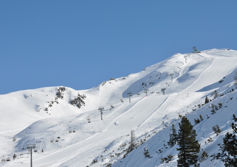 A skier glides down snow-covered slopes at the Reinswald ski resort in South Tyrol Italy. The picturesque scene features a chalet and a majestic mountain in the backdrop.