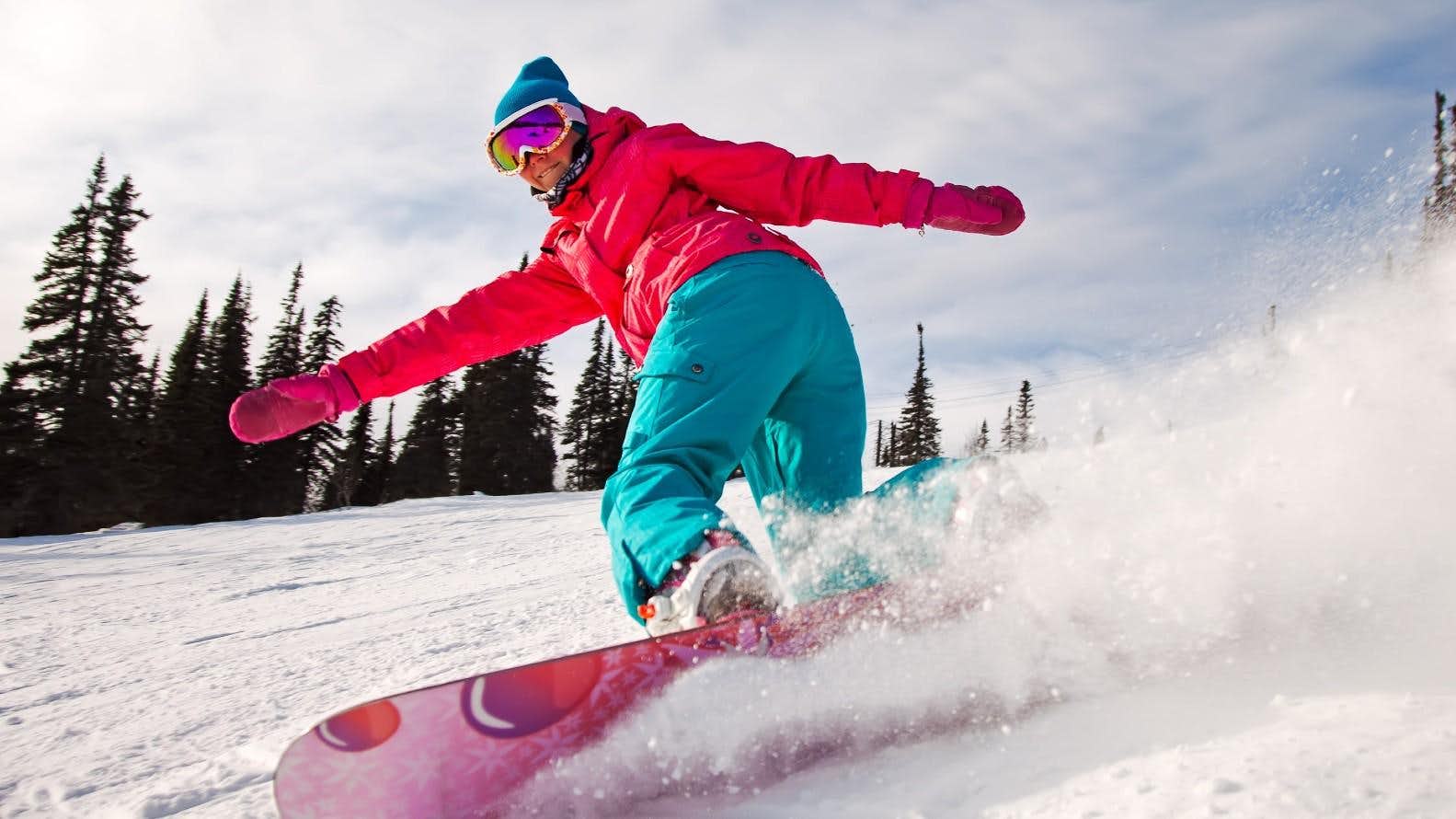 Grünberg – Obsteig in Austria - a woman riding a snowboard down a snow covered slope.