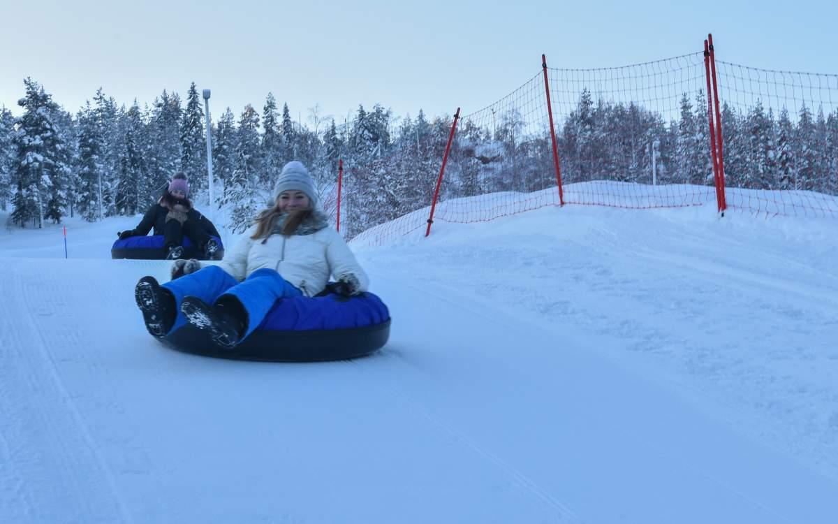 Aavasaksa in Finland - two people are sled down a hill in the snow.