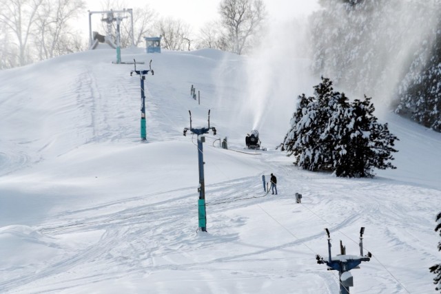 Winter scene at Whitetail Ridge in Fort McCoy, Wisconsin, featuring snow-covered slopes bustling with skiers, sleek ski lifts, and vibrant ski resort facilities.