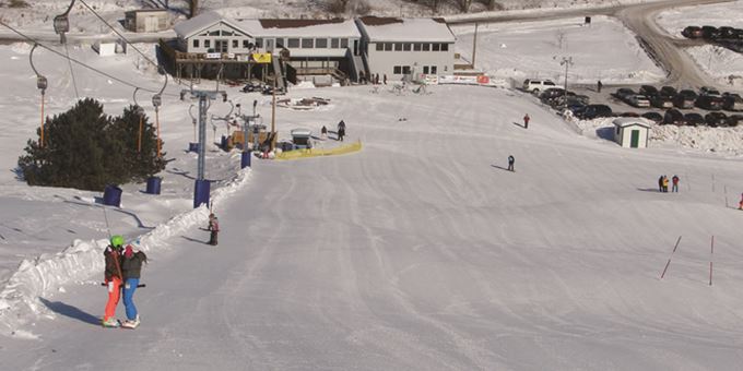 Winter scene at Whitetail Ridge, Fort McCoy in Wisconsin, featuring a bustling ski resort with skiers, a visible ski lift, all cozied in a lively winter sports center.
