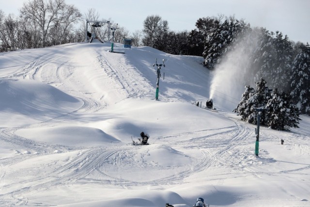 Winter sports scene at Whitetail Ridge, Fort McCoy, Wisconsin, featuring a bustling ski resort with skiers gliding down the snowy slopes and a ski lift in operation.