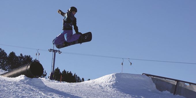 A snowboarder tackles the slopes of Whitetail Ridge in Fort McCoy, Wisconsin. Dusted with fresh snow, the steep incline provides a thrilling ride. Glimpses of bare trees frame the exhilarating scene.