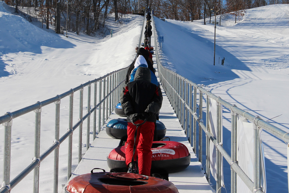 Whitetail Ridge – Fort McCoy in USA - a man riding a snowmobile down a snowy hill.
