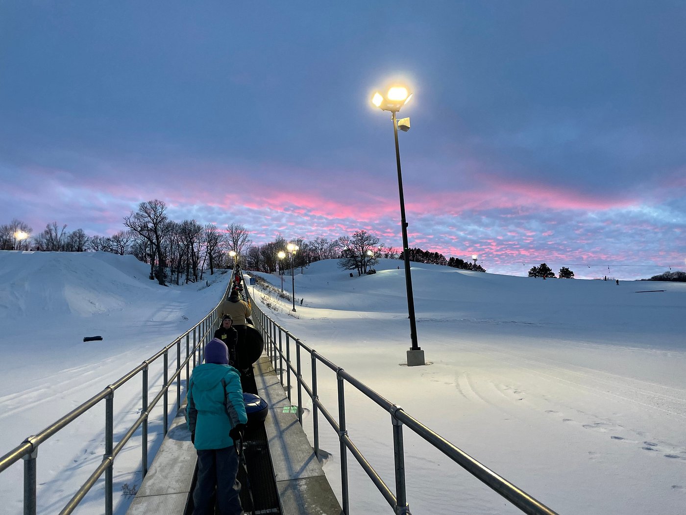 Winter sports enthusiasts enjoying the snowy landscape at Whitetail Ridge, Fort McCoy, Wisconsin, with a charming chalet tucked amidst the pristine scenery.