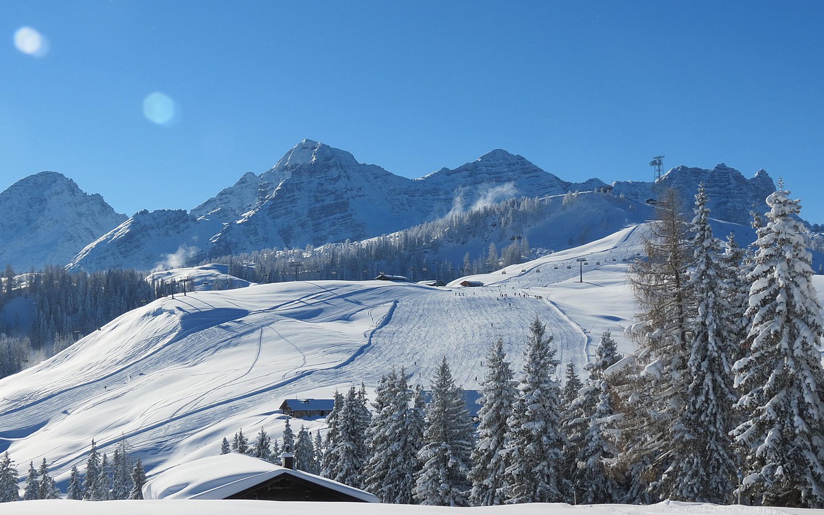 Almenwelt Lofer in Austria - a snow covered mountain with trees in the fore.