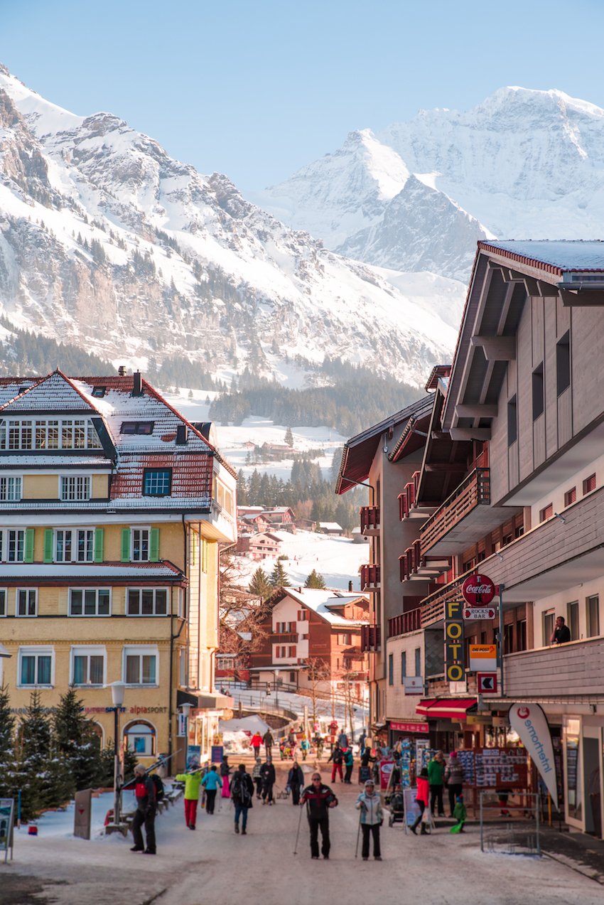 Wengen in Germany - people walking down the street in front of a mountain range.