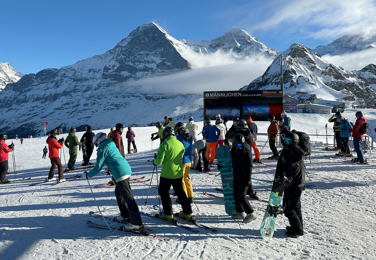 Wengen in Germany - a group of people standing on top of a ski slope.