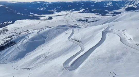 A picturesque view at Ji kepulin - Hemu ski resort in Xinjiang China featuring a charming chalet against the backdrop of winter scenery with scattered skiers enjoying the slopes.