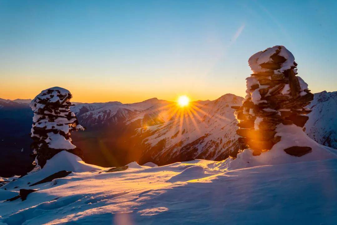 A picturesque scene in Ji kepulin – Hemu Xinjiang China featuring a majestic mountain covered in snow with a winter sports scene unfolding and a lovely challet nestled amidst the stunning winter landscape.