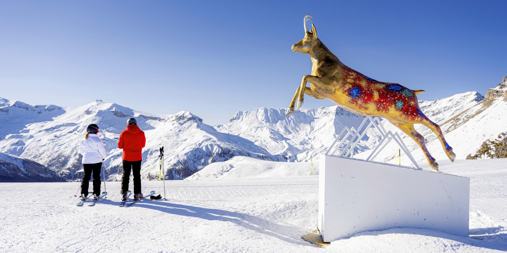 Auron in France - a man standing in the snow next to a statue of a dog.