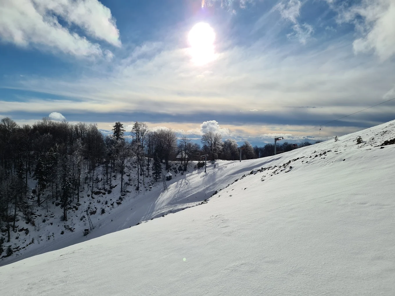 Smestaj"Iver" - Mećavnik - Mokra Gora in Serbia - the sun is shining over a snowy mountain.