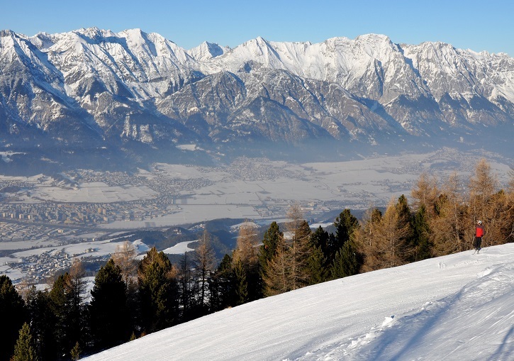 Winter sports enthusiasts enjoying at Patscherkofel ski resort in Innsbruck, Austria, surrounded by stunning winter scenery with a cozy chalet nearby.