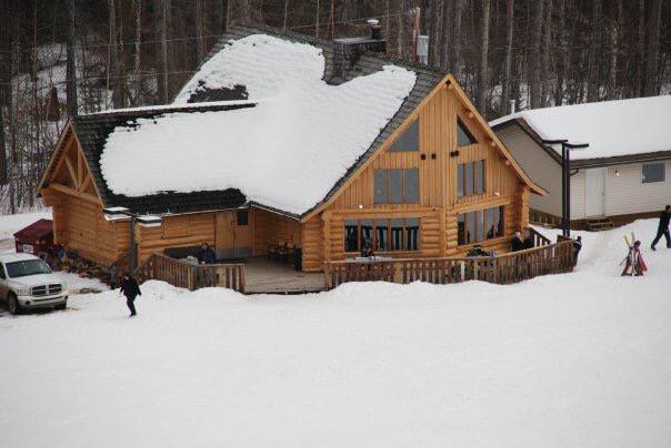 View of Spring Lake Ski Hill in Northern Alberta, Canada with the ski resort and lodge nestled amidst snowy terrain. Winter sports enthusiasts are visible, enjoying the facilities on offer for a day of fun and thrill in the snow.