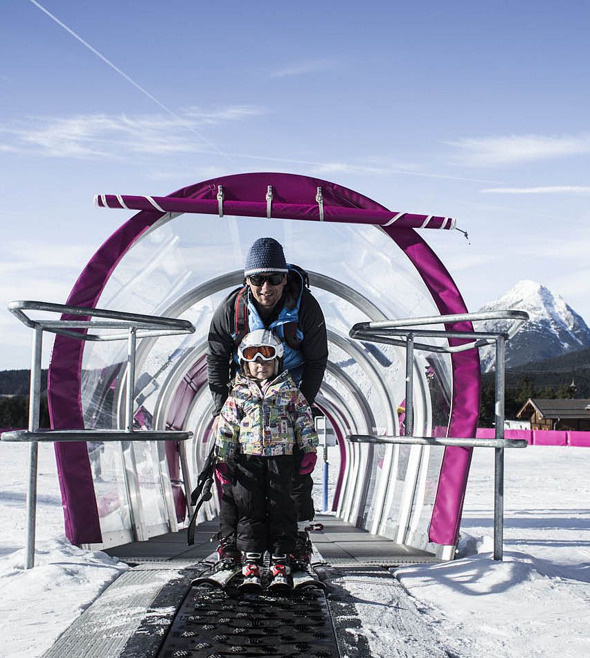 Rosshütte – Seefeld in Austria - a man and a child standing in front of a snow tunnel.