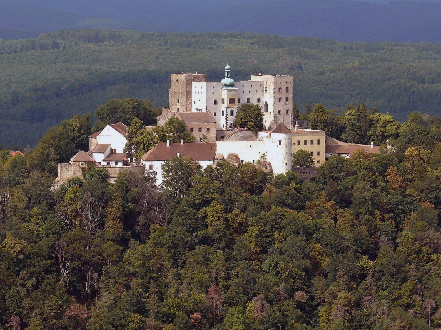 Potštát in Czech Republic - a castle on top of a hill surrounded by trees.