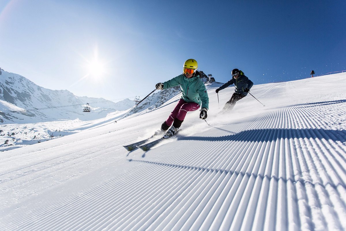 Bergkastelseilbahn Nauders in Austria - two people skiing down a snowy slope.