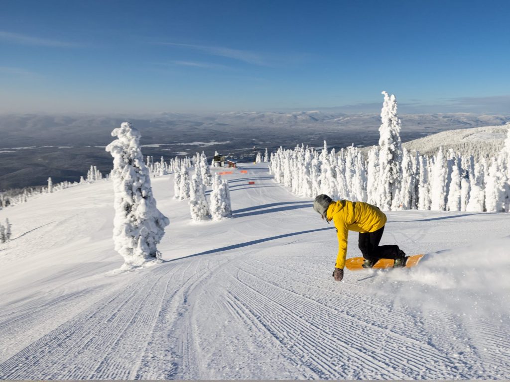Whitefish Mountain Resort in USA - a person snowboarding on a snowy mountain.