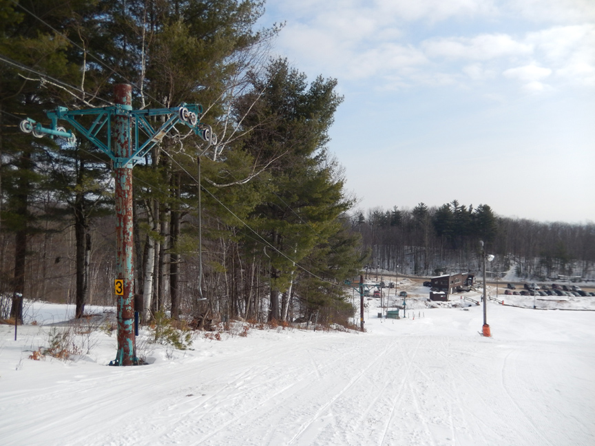 Winter sports scene in Beartown, The Adirondacks, showcasing a bustling ski lift against a backdrop of a charming chalet and the vibrant ski resort.
