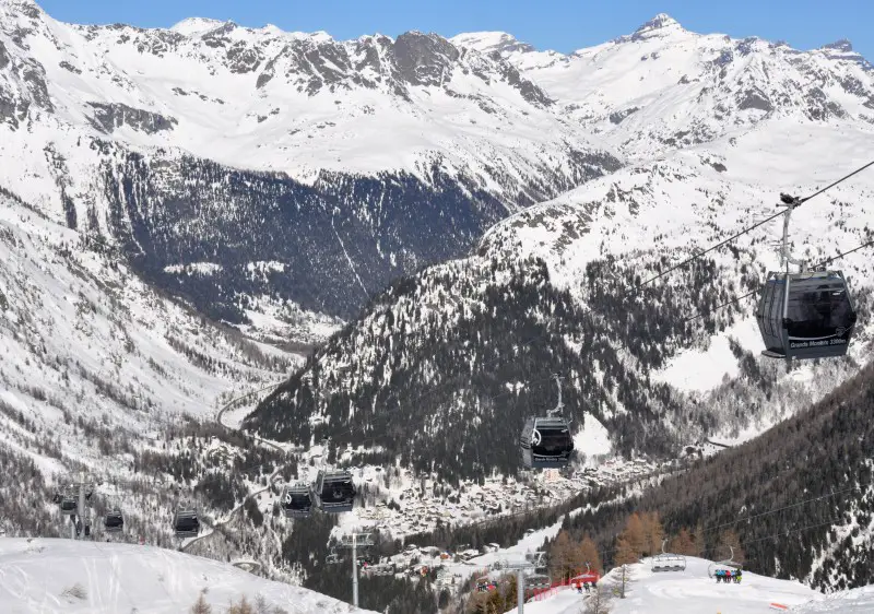A winter scene from Grands Montets ski resort in Argentière, France, featuring a charming chalet nestled amongst snow-covered mountains under a clear sky.